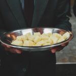 Edelstahl Dörrautomat mit zehn Einschüben, gefüllt mit Apfelringen, Kräutern und Pilzen, zur Haltbarmachung von Lebensmitteln.